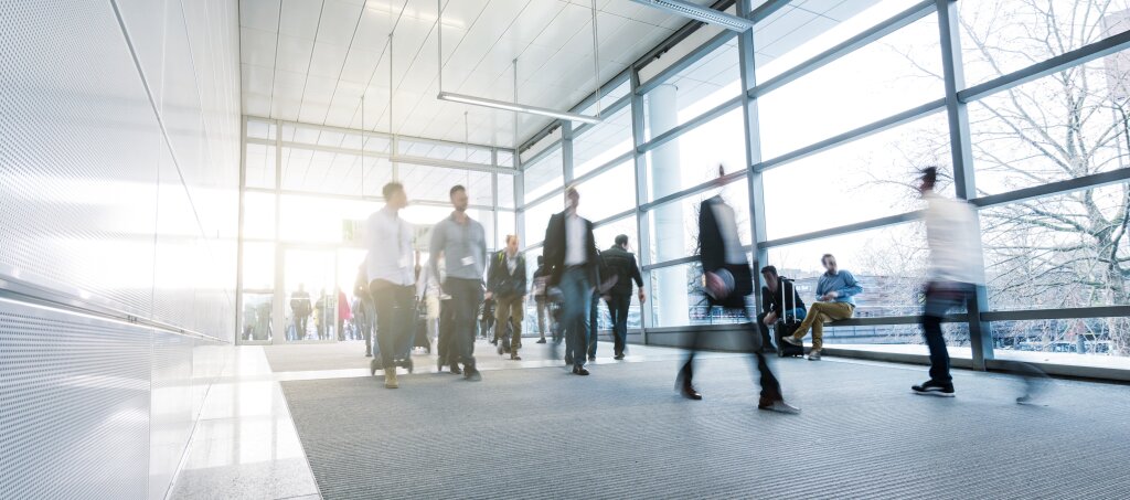 Airport walkway with people walking in and out of door.